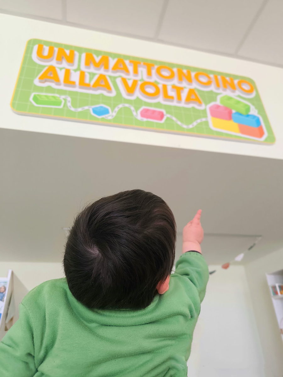Bambino indica il cartello di Un Mattoncino alla Volta